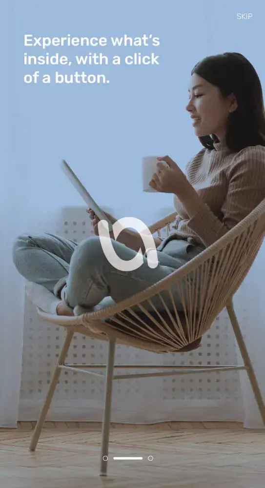 A woman sitting on a modern wicker chair, holding a cup and interacting with a tablet, with The Voucher App Logo superimposed on the image, accompanied by the slogan 'Experience what's inside, with a click of a button.